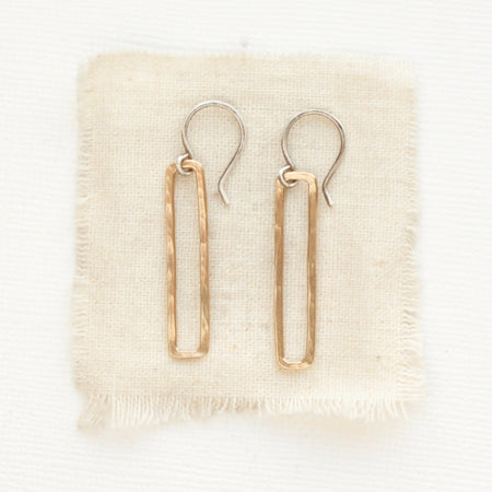 The bronze open bar earrings styled on tan linen