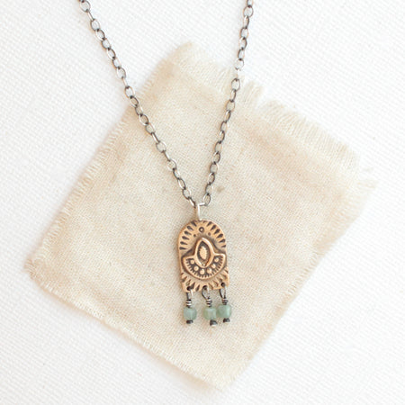 The bronze wanderer arch green apatite necklace styled on tan linen
