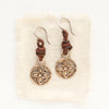 The bronze wanderer coin leather earrings styled on tan linen