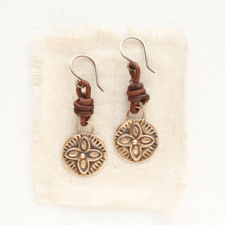 The bronze wanderer coin leather earrings styled on tan linen