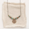 The bronze wanderer coin lona necklace styled on tan linen