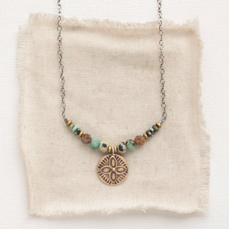 The bronze wanderer coin lona necklace styled on tan linen