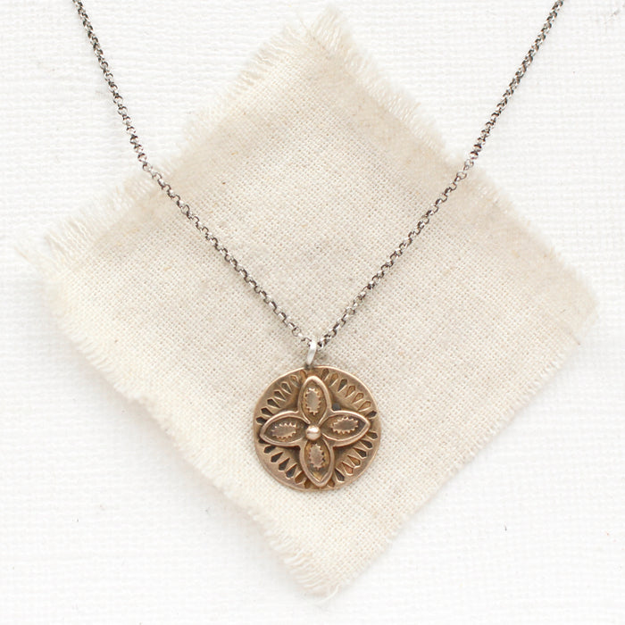 The bronze wanderer coin necklace styled on tan linen