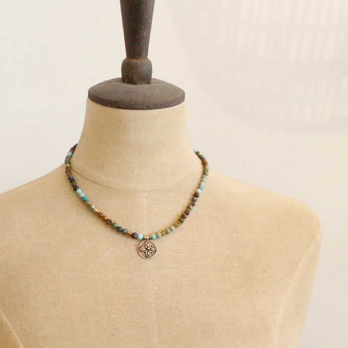A mannequin wearing the bronze wanderer coin turquoise ombre necklace 