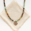 The bronze wanderer coin turquoise ombre necklace styled on tan linen
