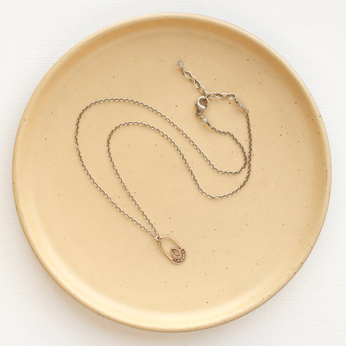 The bronze wanderer hoop necklace styled on a tan plate to show the adjustable lobster clasp closure