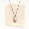 The bronze wanderer hoop necklace styled on tan linen