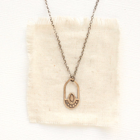 The bronze wanderer hoop necklace styled on tan linen