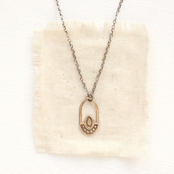 The bronze wanderer hoop necklace styled on tan linen