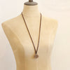 A mannequin wearing the bronze medallion leather necklace in the long style