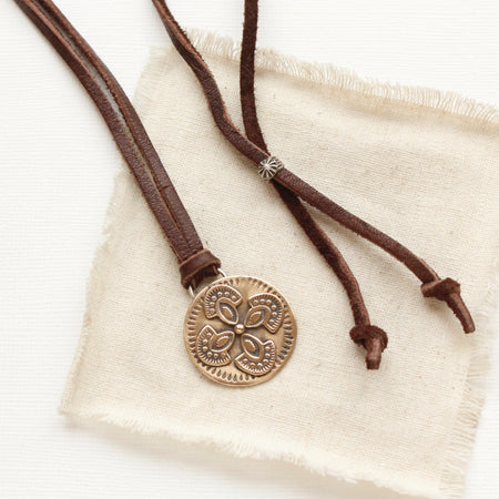 The bronze wanderer medallion leather necklace styled on tan linen