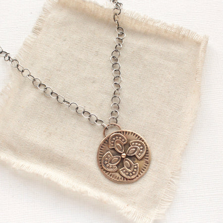 The bronze wanderer medallion necklace styled on tan linen