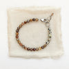 The brown zircon and dalmatian jasper bracelet styled on tan linen