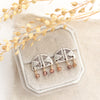 The brown zircon mixed metal pakal arch post earrings styled on tan linen with dried grass