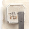 A brown zircon pakal arch post earring next to a ruler for size reference