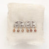 The brown zircon pakal arch post earrings styled on tan linen