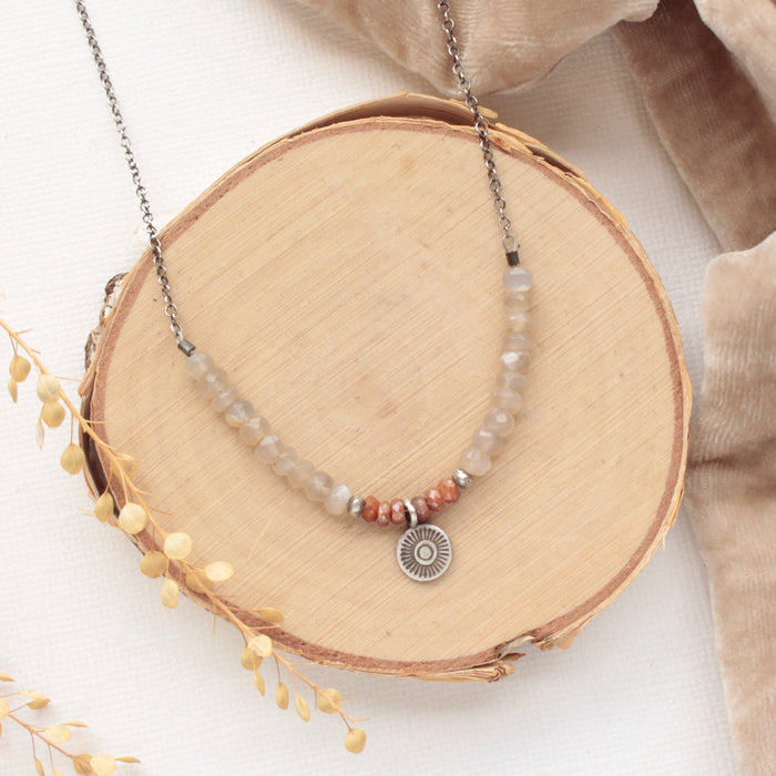 The talara sun zaria necklace styled on wood with tan velvet and dried grass