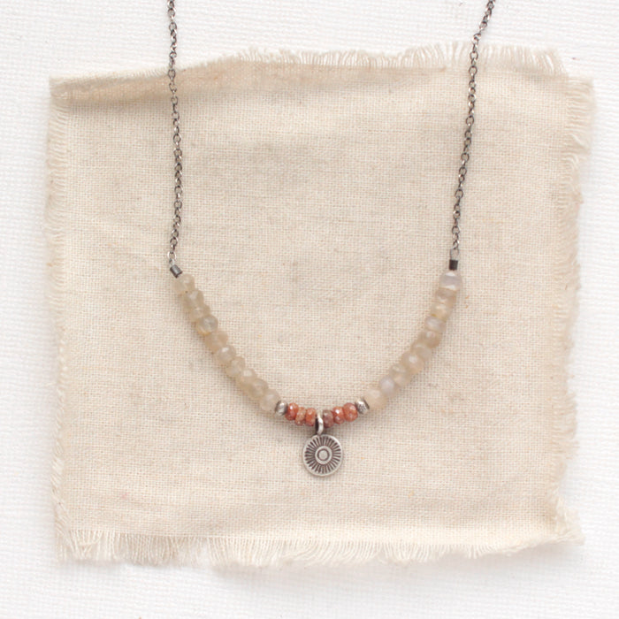 The talara sun zaria necklace styled on tan linen