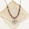 The brown zircon wanderer medallion necklace styled on tan linen