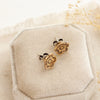 The bronze mini cactus flower post earrings styled on a velvet box to show the butterfly earbacks