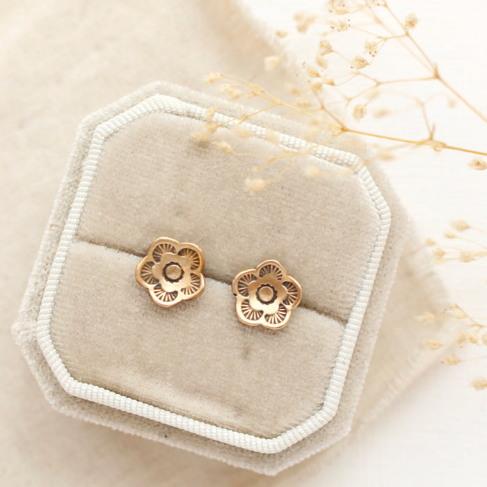 The bronze mini cactus flower post earrings styled on a velvet box with linen and dried grass
