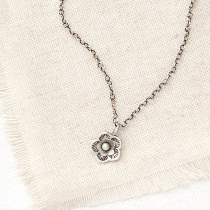 The mini cactus flower necklace styled on tan linen