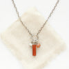 The pear, red jasper, and sunstone charm necklace styled on tan linen.