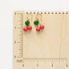 The little cherry earrings on a wooden ruler for size reference. 