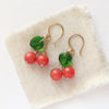 The little cherry earrings styled on tan linen