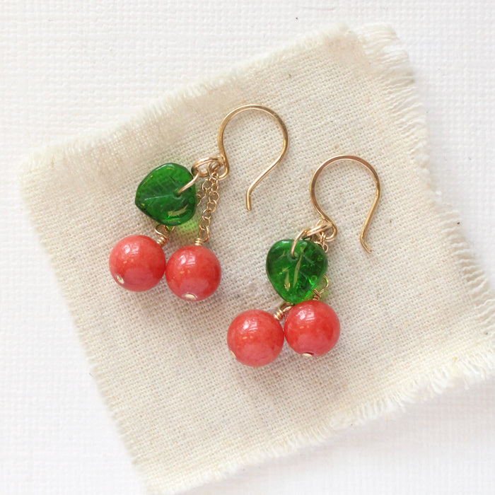 The little cherry earrings styled on tan linen