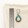 A chrysocolla hoop earring next to a ruler for size reference