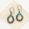 The chrysocolla hoop earrings styled on tan linen