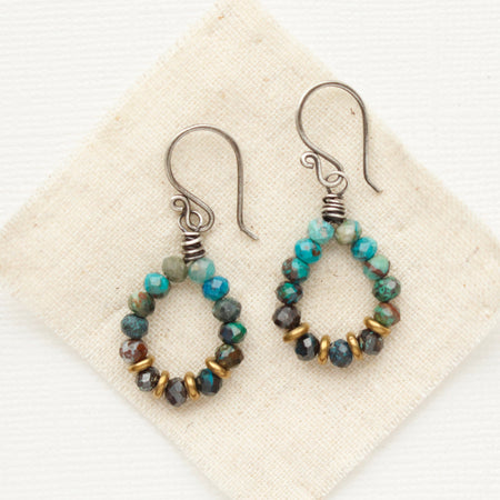 The chrysocolla hoop earrings styled on tan linen