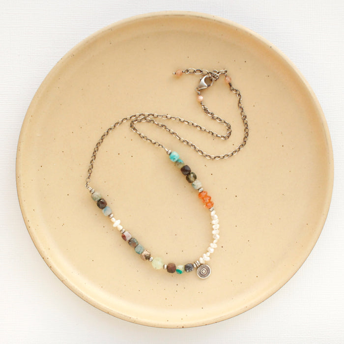 The talara sun mesa necklace styled on a tan plate to show the adjustable lobster clasp closure