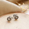 The columbine burst post earrings styled on wood with tan velvet and dried grass
