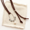 The columbine hoop pearl adjustable leather necklace styled on tan linen