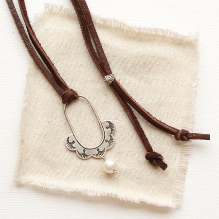 The columbine hoop pearl adjustable leather necklace styled on tan linen