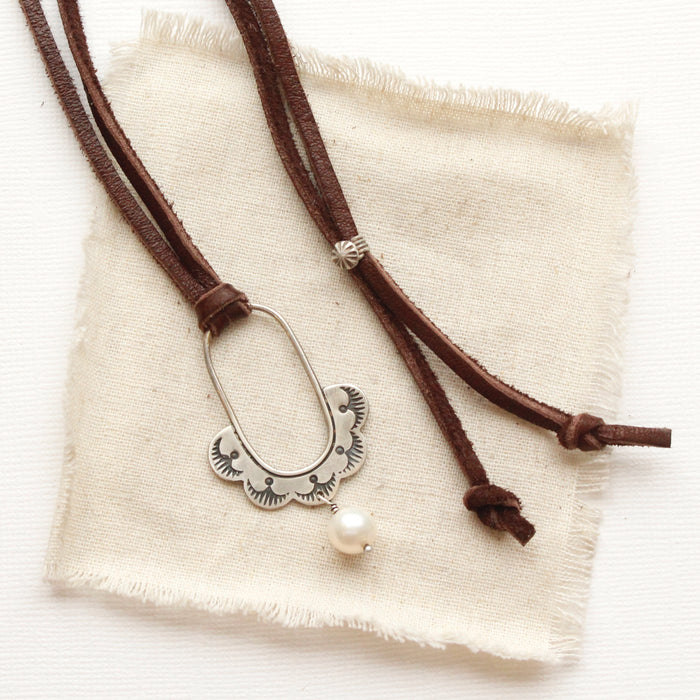 The columbine hoop pearl adjustable leather necklace styled on tan linen
