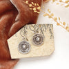 The columbine medallion earrings styled on a tan rock with orange velvet and dried grass