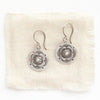 The columbine medallion earrings styled on tan linen
