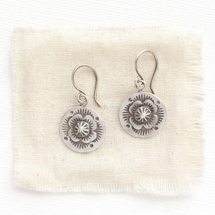 The columbine medallion earrings styled on tan linen