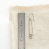 A dalmatian jasper forged long hoop earrning styled next to a ruler for size reference