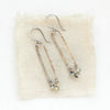 The dalmatian jasper long forged hoop earrings styled on tan linen