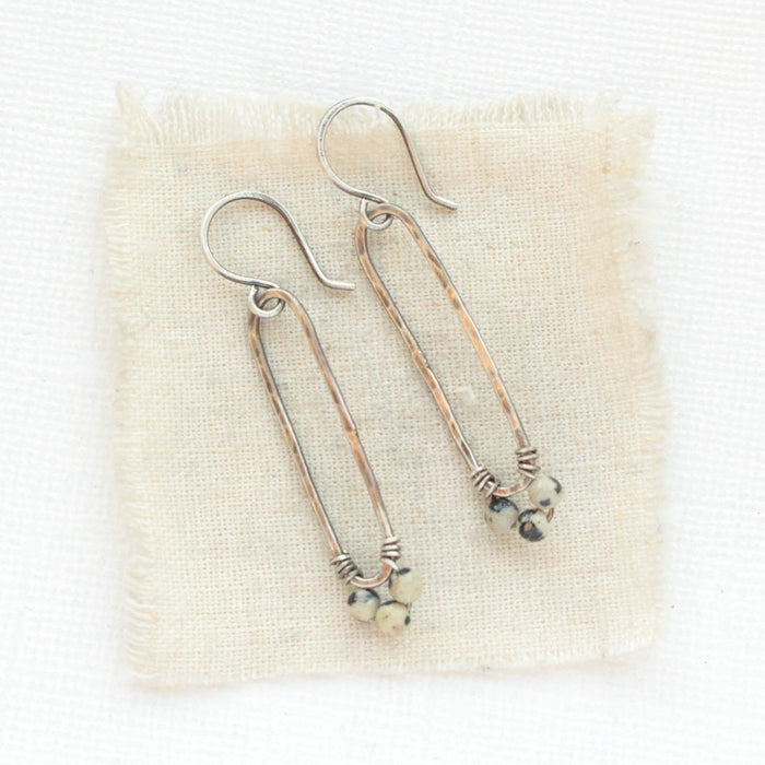 The dalmatian jasper long forged hoop earrings styled on tan linen