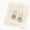 The embossed silver disc earrings styled on tan linen