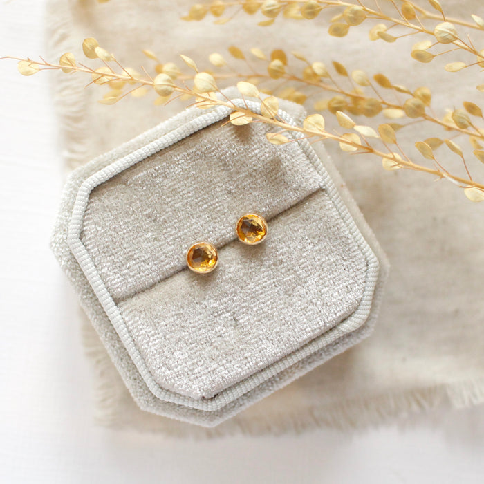 The citrine post earrings styled on a velvet box with linen and dried grass