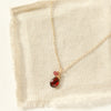 The garnet charm necklace styled on tan linen