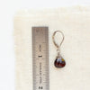 A garnet drop earring next to a ruler for size reference