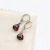 The garnet drop silver earrings styled on tan linen