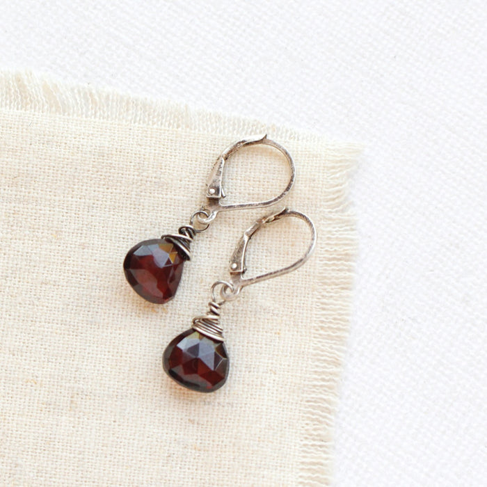 The garnet drop silver earrings styled on tan linen